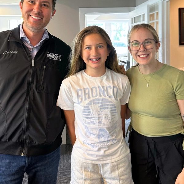 Smiling young patient with Dr. Scherer and team member, creating a warm and welcoming orthodontic experience.