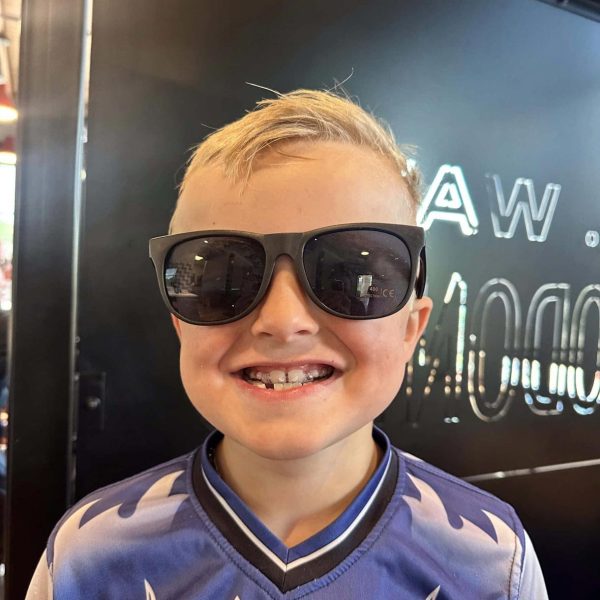 Young boy with a joyful smile and sunglasses in the Dr. Wax Orthodontics office.