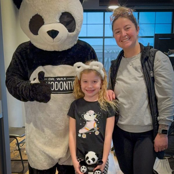 Child smiling warmly with an adult and a panda mascot at Dr. Wax Orthodontics.