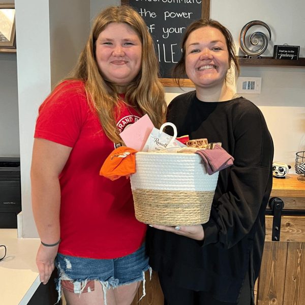 Two smiling people happily holding a gift basket at Dr. Wax Orthodontics.