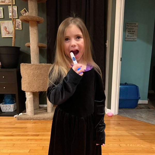 Child playfully using a thermometer in a cozy home setting.